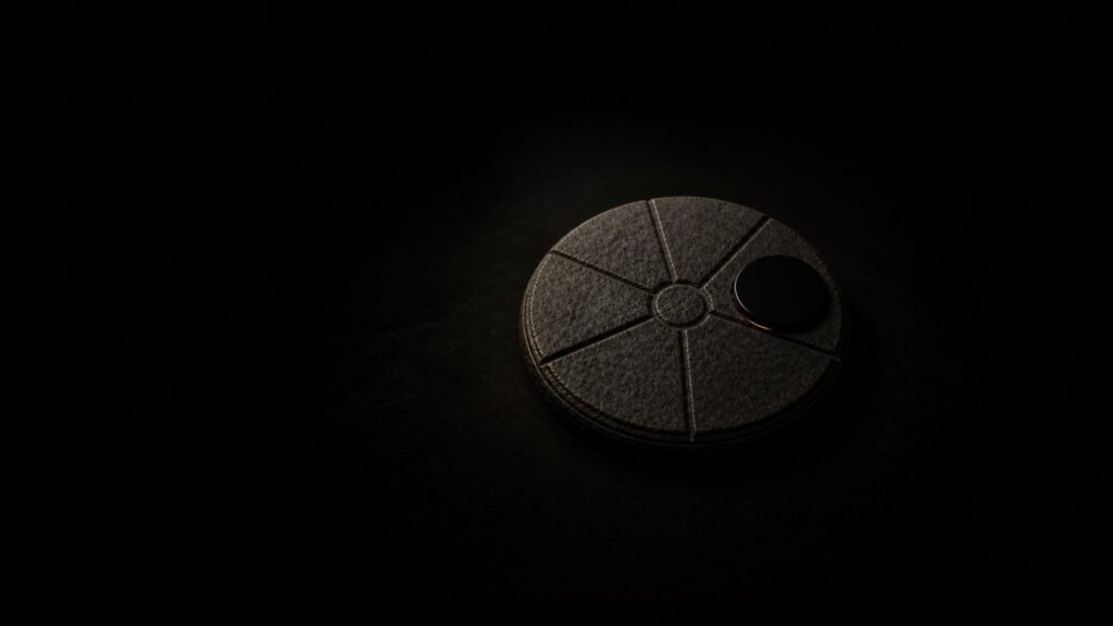 A carved stone disc divided into seven segments, with a glossy black medallion substituted over part of the seventh, a sliver of the true marking still visible beneath it